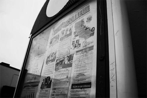 Scratch marks all over an announcement board, carved into the plexiglass and metal frame. 